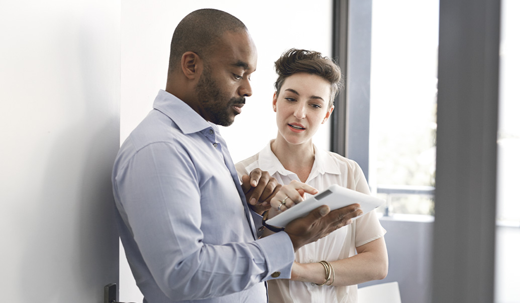 Coworkers standing up and looking at tablet together