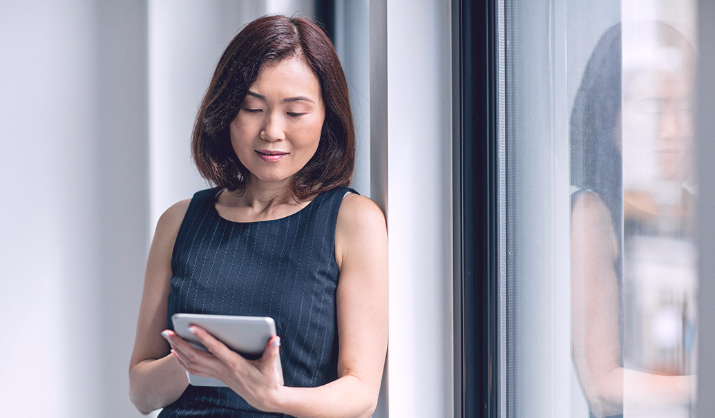 Woman standing next to window with tablet